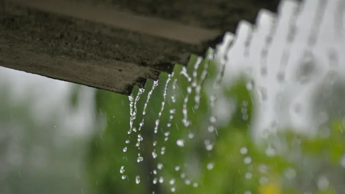 Rainwater overflowing from a blocked gutter on a UK house during heavy rain